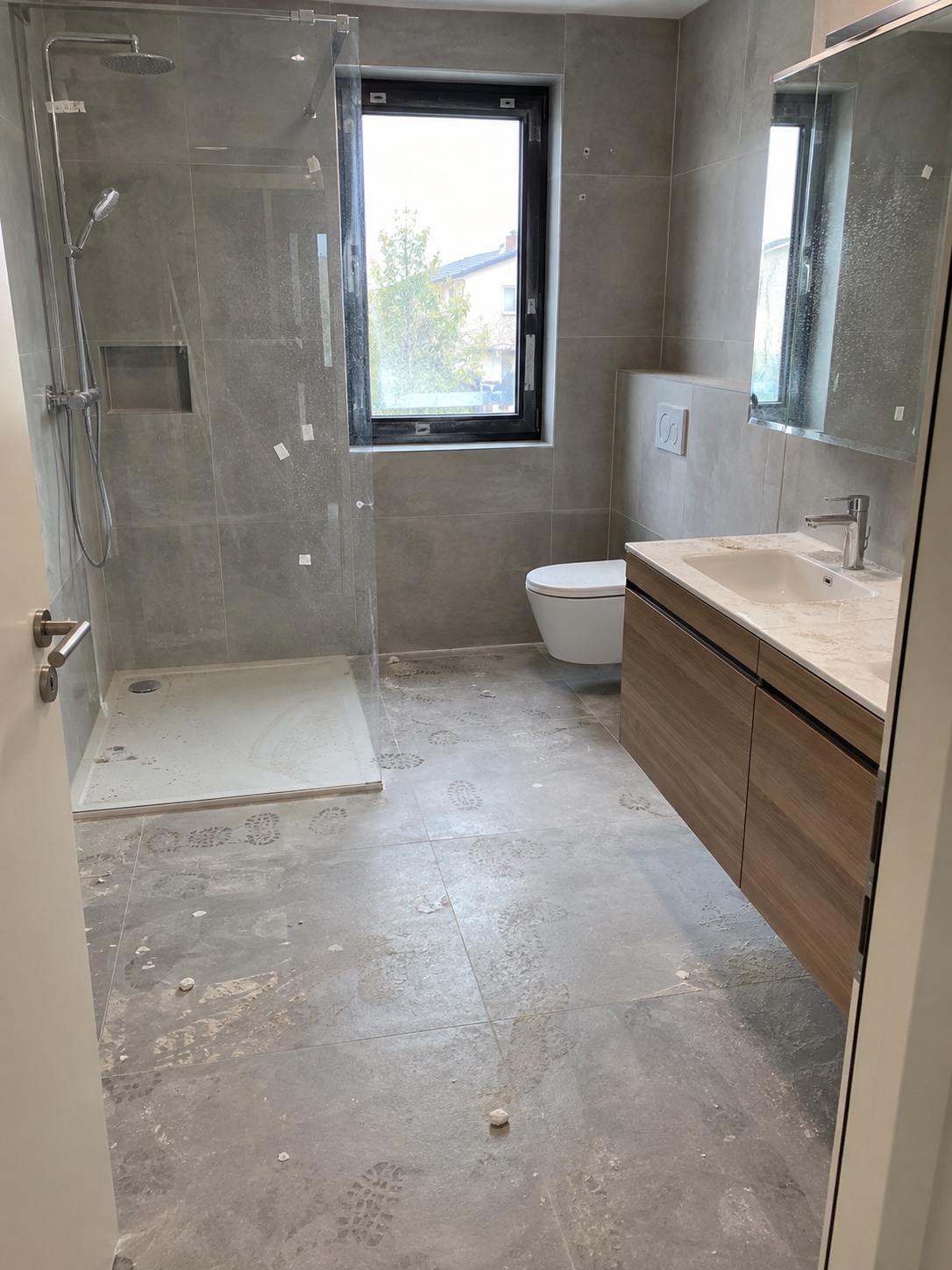 Modernes Badezimmer vor der Bauendreinigung mit Baustaub, Schuhspuren und Rückständen auf Fliesen und Glas