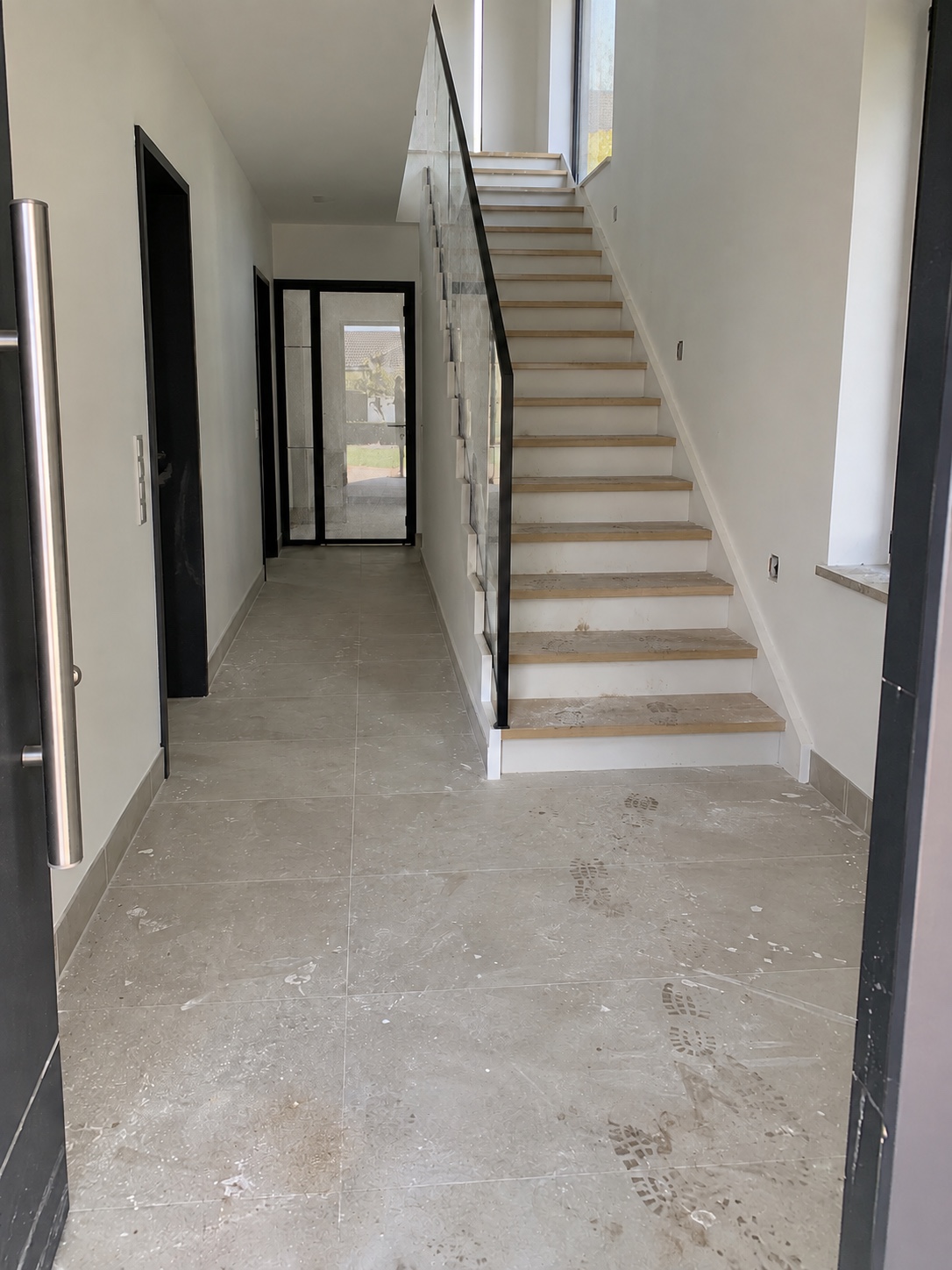 Flur und Treppenhaus vor der Bauendreinigung mit Staub, Schuhspuren und verschmutzten Glasflächen