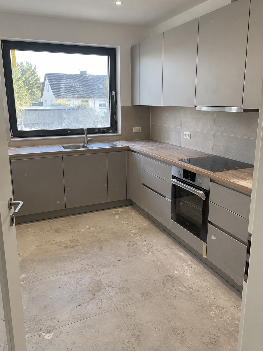 Neu eingebaute Küche vor der Bauendreinigung mit Baustaub, Schuhspuren, Spritzern und Folienresten