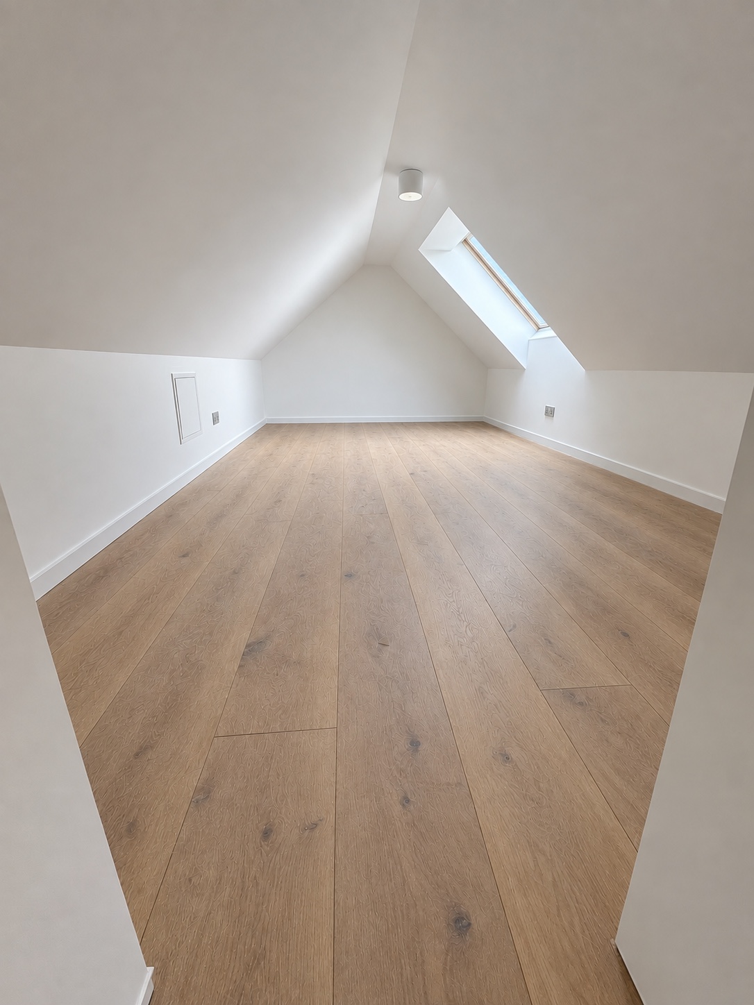 Der Dachboden zeigt sich mit sauberem Boden und freien Flächen. Die Holzmaserung ist deutlich sichtbar; Karton und lose Renovierungsrückstände sind entfernt