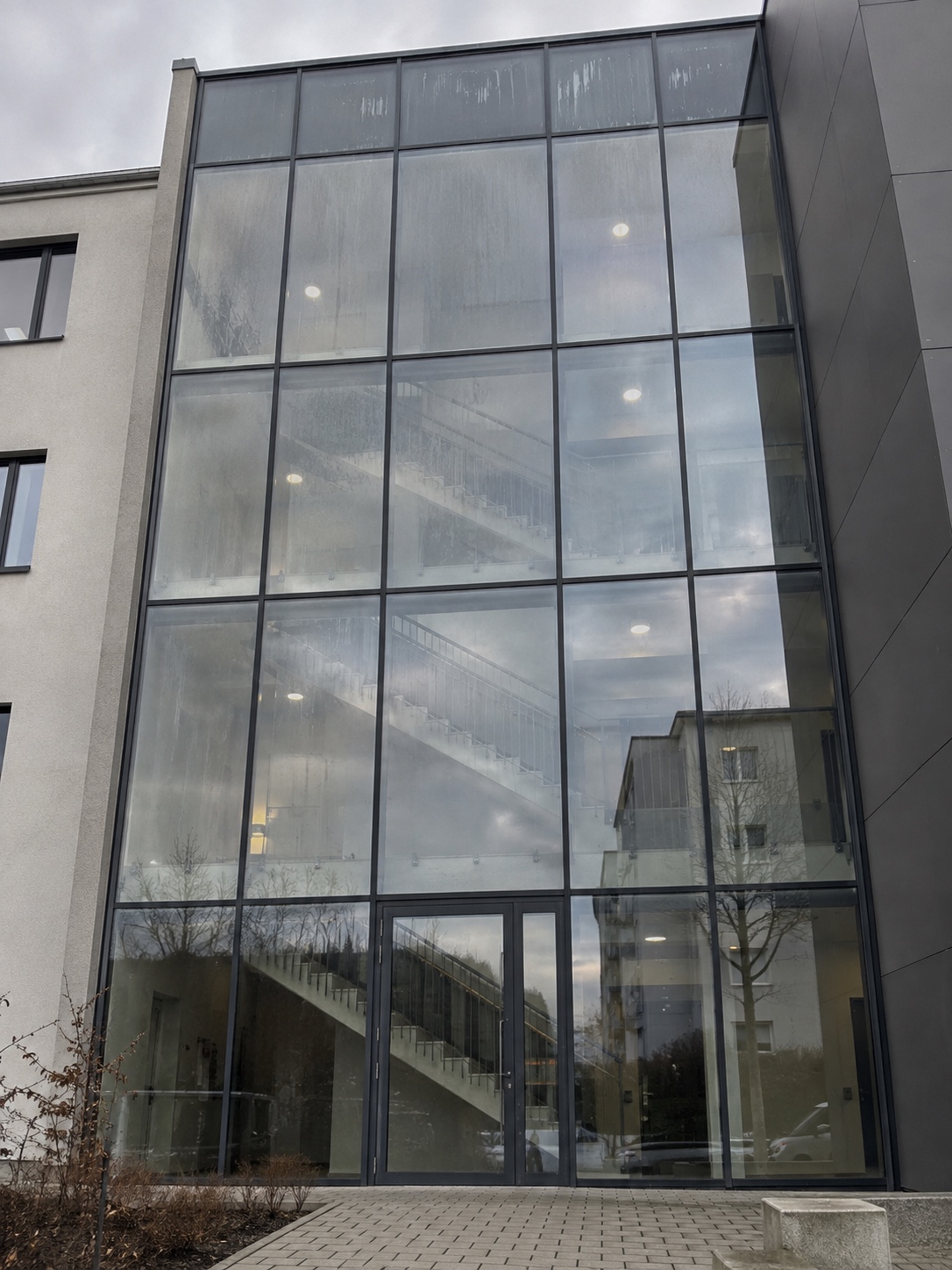 Mehrgeschossige Treppenhausverglasung mit fleckigen Scheiben und Laufspuren